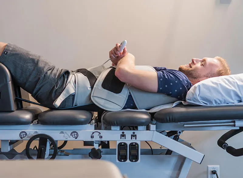 Patient lying on a spinal decompression table with a harness around the waist